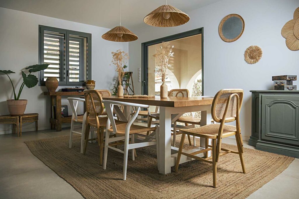 Salle à manger ouverte avec portes vitrées volets fermés, menuiserie moderne gris, mobilier bois naturel, luminaires suspendus