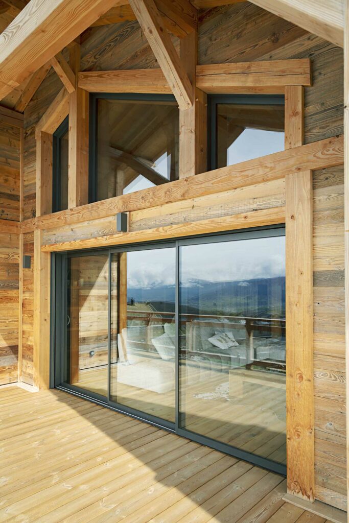 Portes-fenêtres coulissantes bois massif, cadres naturels, terrasse chalet vue montagne, vitrage panoramique