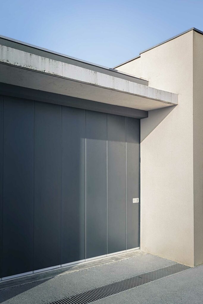 Porte de garage coulissante horizontale aluminium gris, panneaux lames, façade contemporaine, motorisée