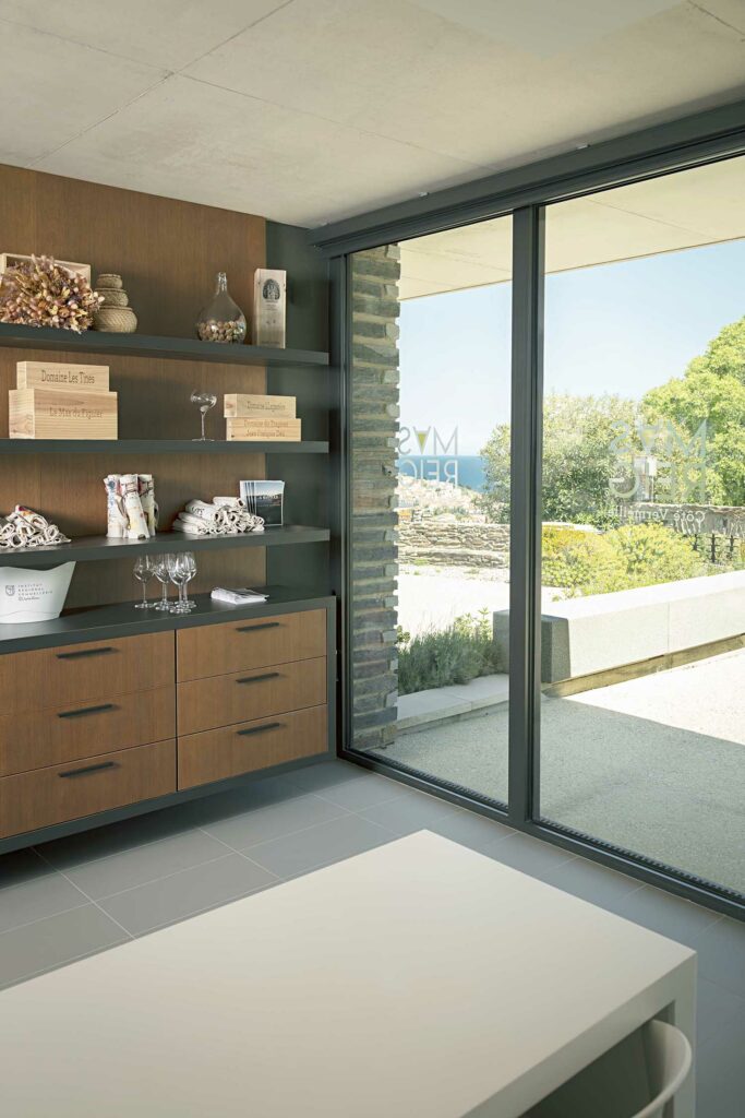Baie vitrée gris foncé bureau oenologie, rangements bois intégrés, vue domaine viticole